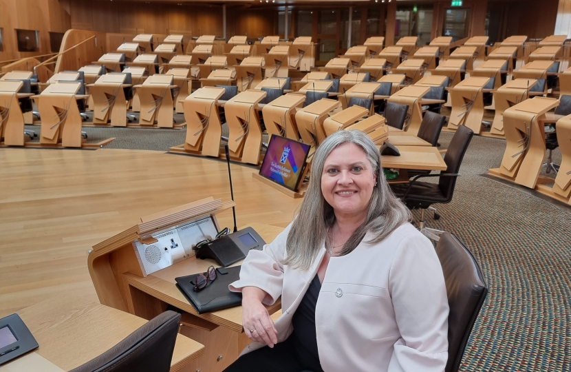 Roz McCall MSP sitting at a desk in the Chamber in the Scottish Parliament